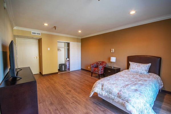 A private resident room with a bed and chair