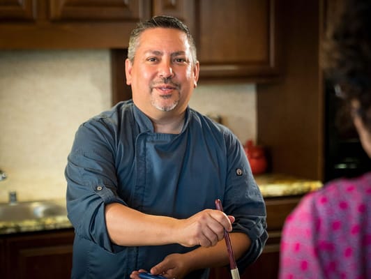 Chef interacting with a resident in a kitchen setting