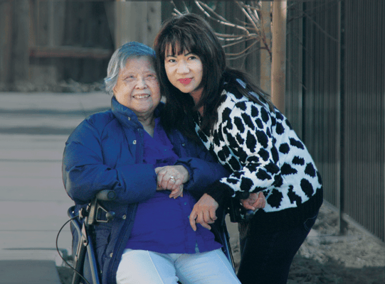 A caregiver with a resident posing in a garden area