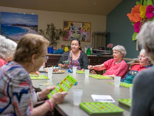 Residents playing bingo in a bright activity room