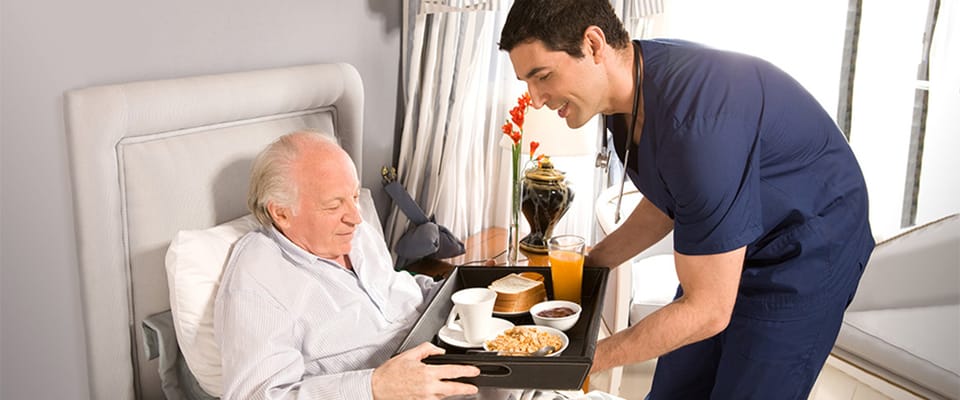 Caregiver delivering food to a resident in bed