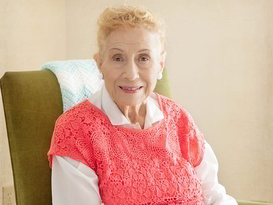 Senior resident smiling in a cozy chair