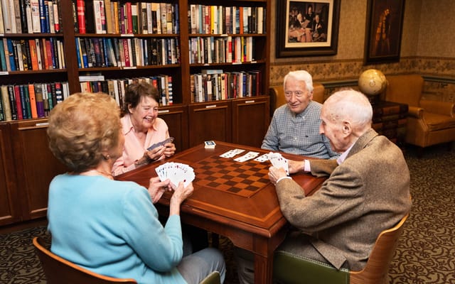 Four residents playing cards in a cozy lounge