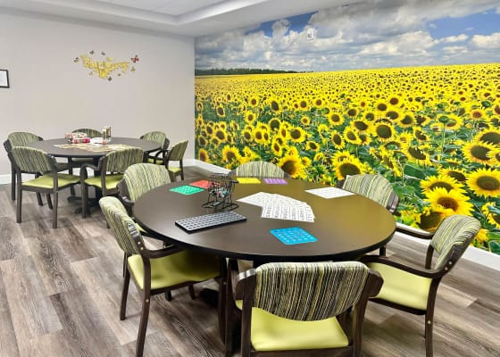 Activity room with tables and sunflower mural