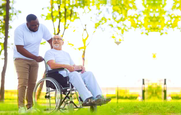 A caregiver assisting a resident in a wheelchair outdoors