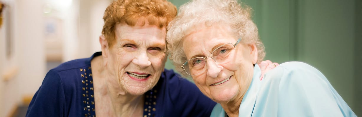 Two smiling elderly residents posing together