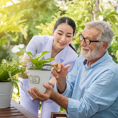 A staff member assisting a resident with a plant