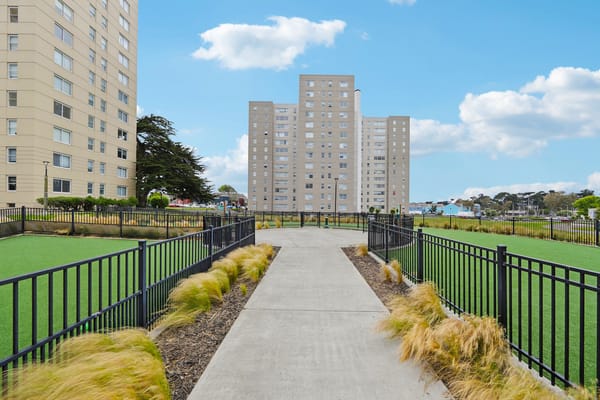 Pathway leading through a landscaped area with buildings in the background