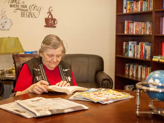 Resident reading in a common area with bookshelves