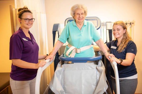 Staff assisting a resident with physical therapy equipment