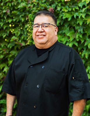 Chef smiling in front of a green backdrop