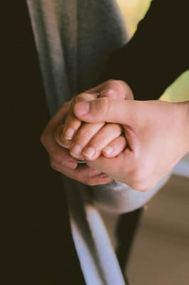 Two hands clasped together in a caring gesture