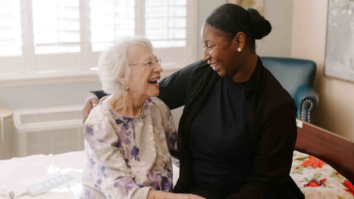 A resident and staff member sharing a joyful moment in a room