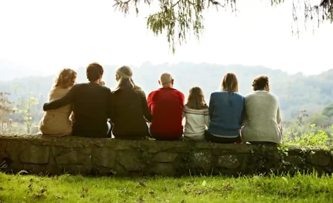 A group of people sitting on a stone wall outdoors