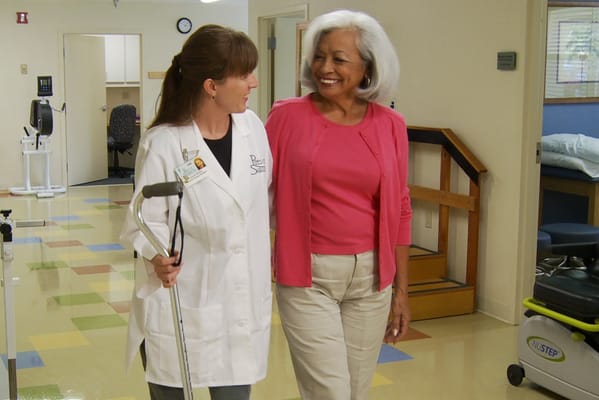 A staff member and resident interacting in a facility hallway