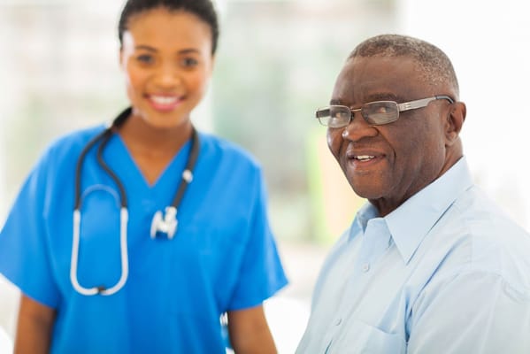A smiling nurse with an elderly man in a bright room