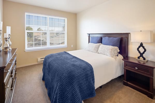 A well-furnished resident room with a bed and dresser