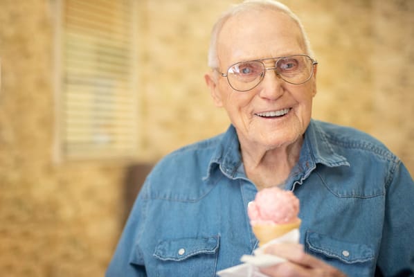 A smiling elderly man holding an ice cream cone