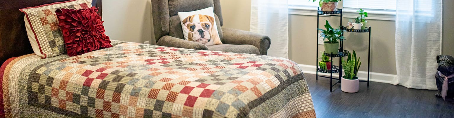 Cozy resident room with a quilt and armchair
