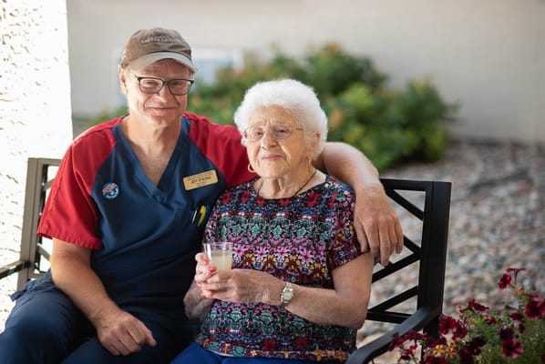 Staff member with resident outdoors, enjoying a drink