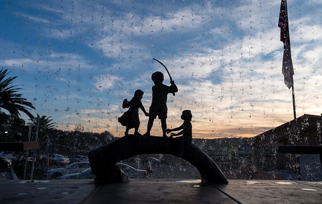 Sculpture of children playing silhouetted against a sunset