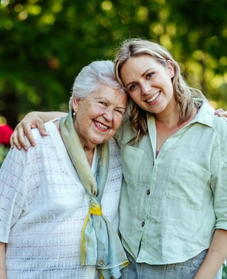 A happy resident and staff member smiling together outdoors