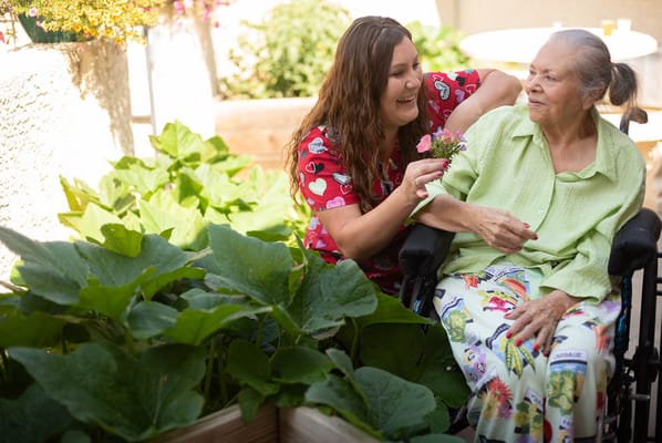 A caregiver interacting with a resident in a garden.
