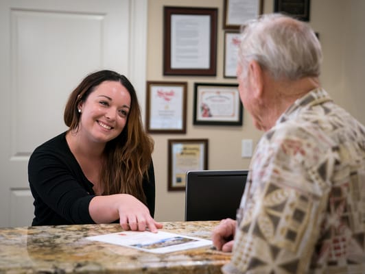 Staff member assisting a resident at the reception desk