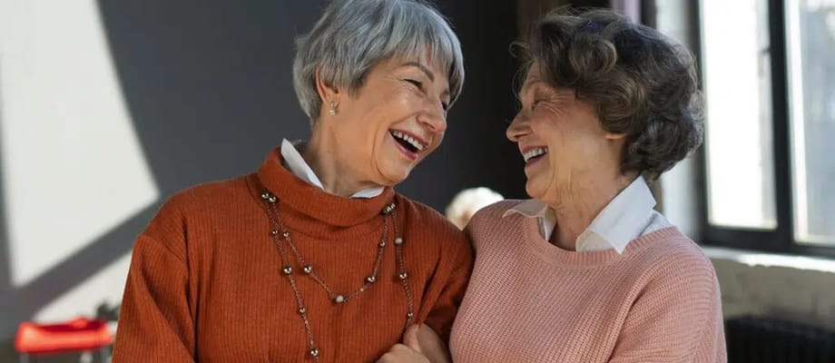 Two senior women laughing together indoors