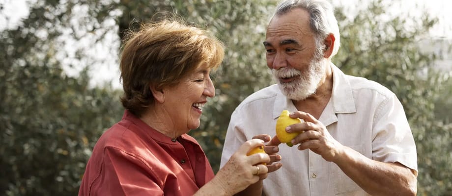 Two seniors smiling and holding lemons outdoors
