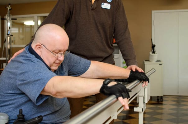 A staff member assisting a resident with rehabilitation exercises