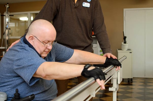 A staff member assisting a resident with rehabilitation exercises
