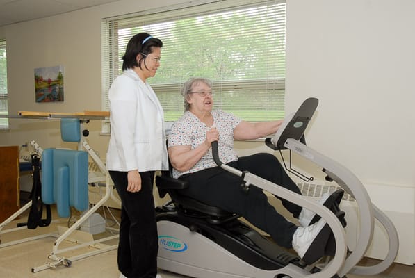 A resident exercising with staff assistance in a therapy room