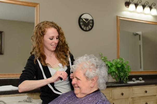 Resident receiving a haircut from a staff member