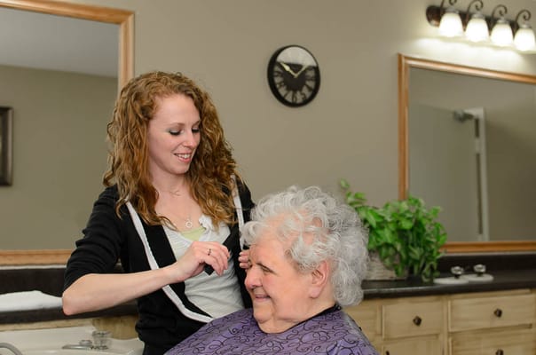 Resident receiving a haircut from a staff member