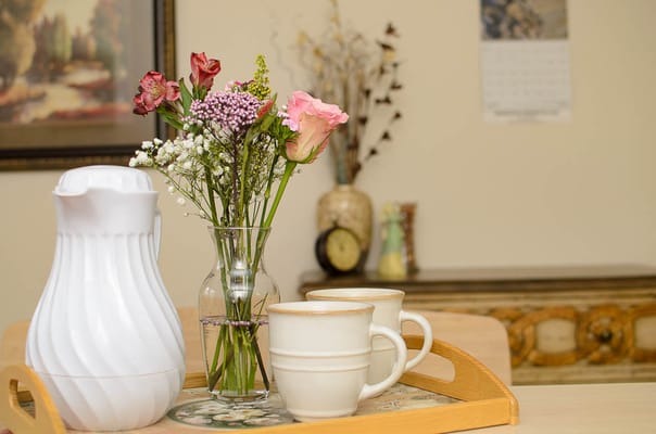 A cozy table setting with flowers and mugs in an interior space