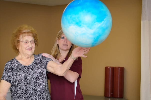 A resident and staff member engaged in an activity with a ball.
