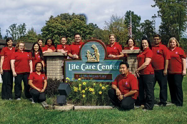 Staff members in front of the facility sign