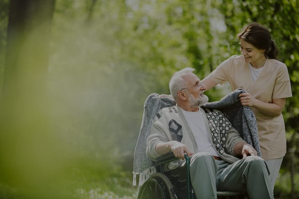 Caregiver assisting a resident in a wheelchair outdoors