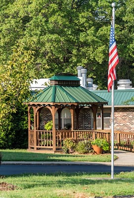 A gazebo surrounded by trees and a flag