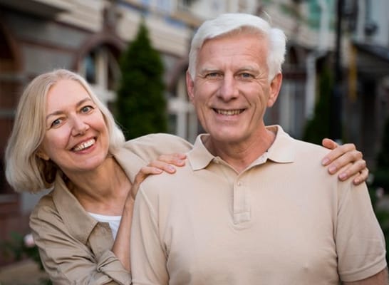 Senior couple smiling outdoors in a community setting