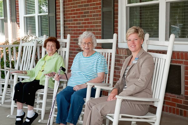 Three residents enjoying rocking chairs on a porch