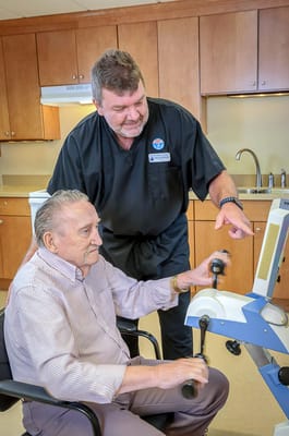 A staff member assisting a resident with exercise equipment