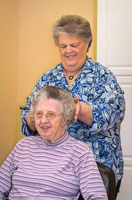 Staff member styling resident's hair in beauty salon