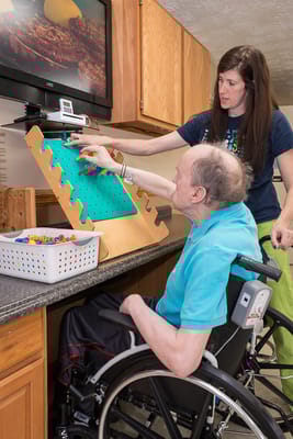 Staff assisting a resident with a sensory activity in the facility