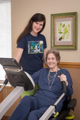 Staff assisting a resident with exercise equipment