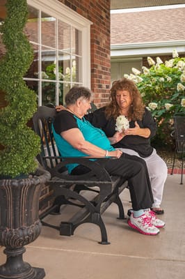 Two residents enjoying time together on a bench outside