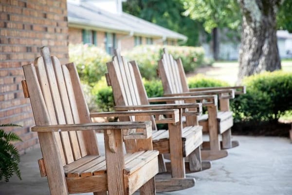 Three wooden rocking chairs on a patio.