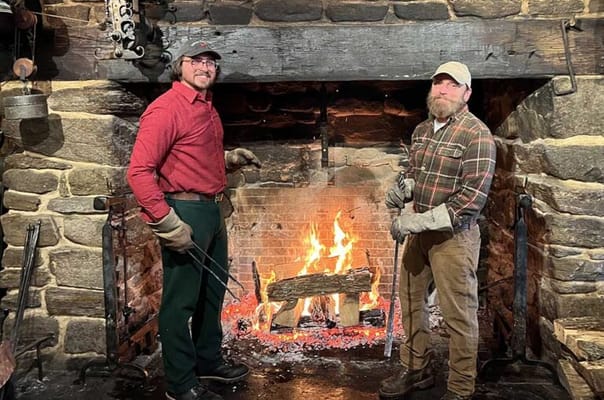 Two staff members standing by a fireplace