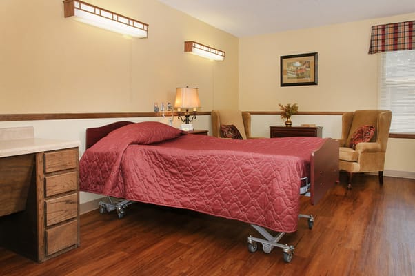 Simple private resident room with a bed and chairs